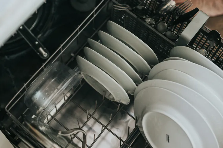 Open dishwasher rack loaded with clean white plates