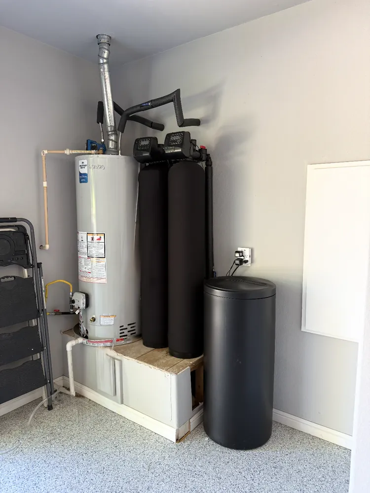 TAC water treatment system installed in a garage: water heater with twin conditioner tanks and brine tank